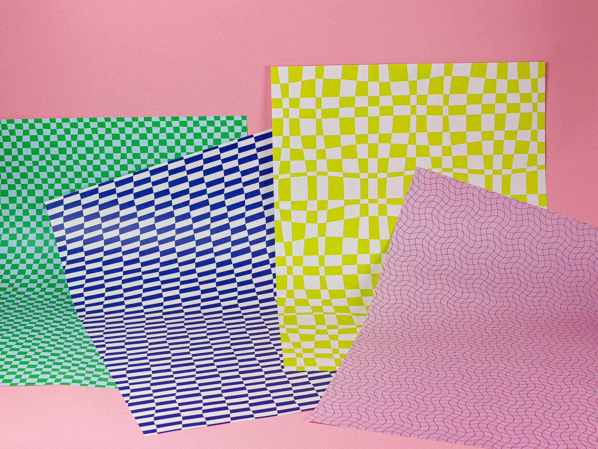 a group of four different colored papers on a pink background