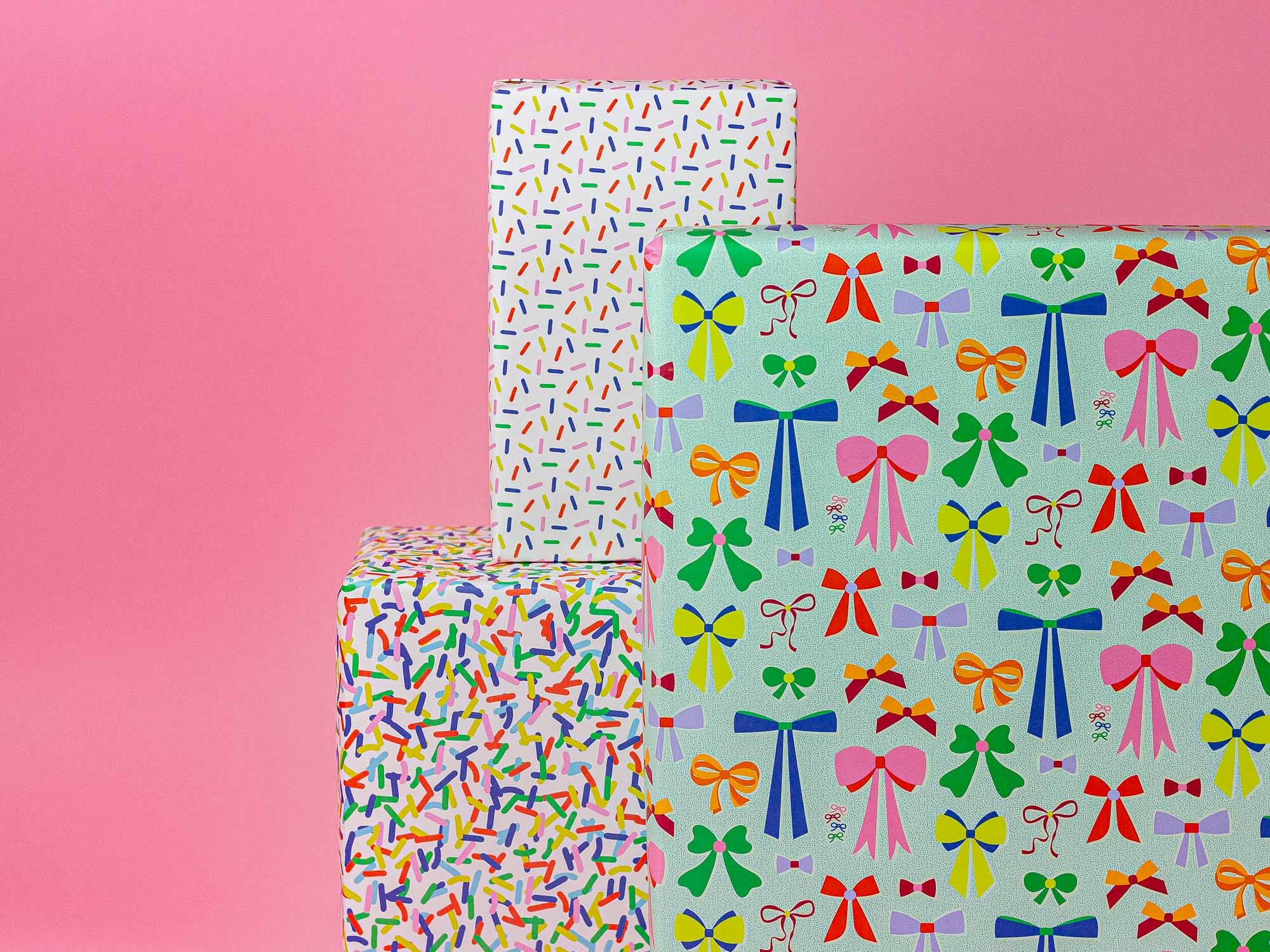 three boxes with bows on them against a pink background