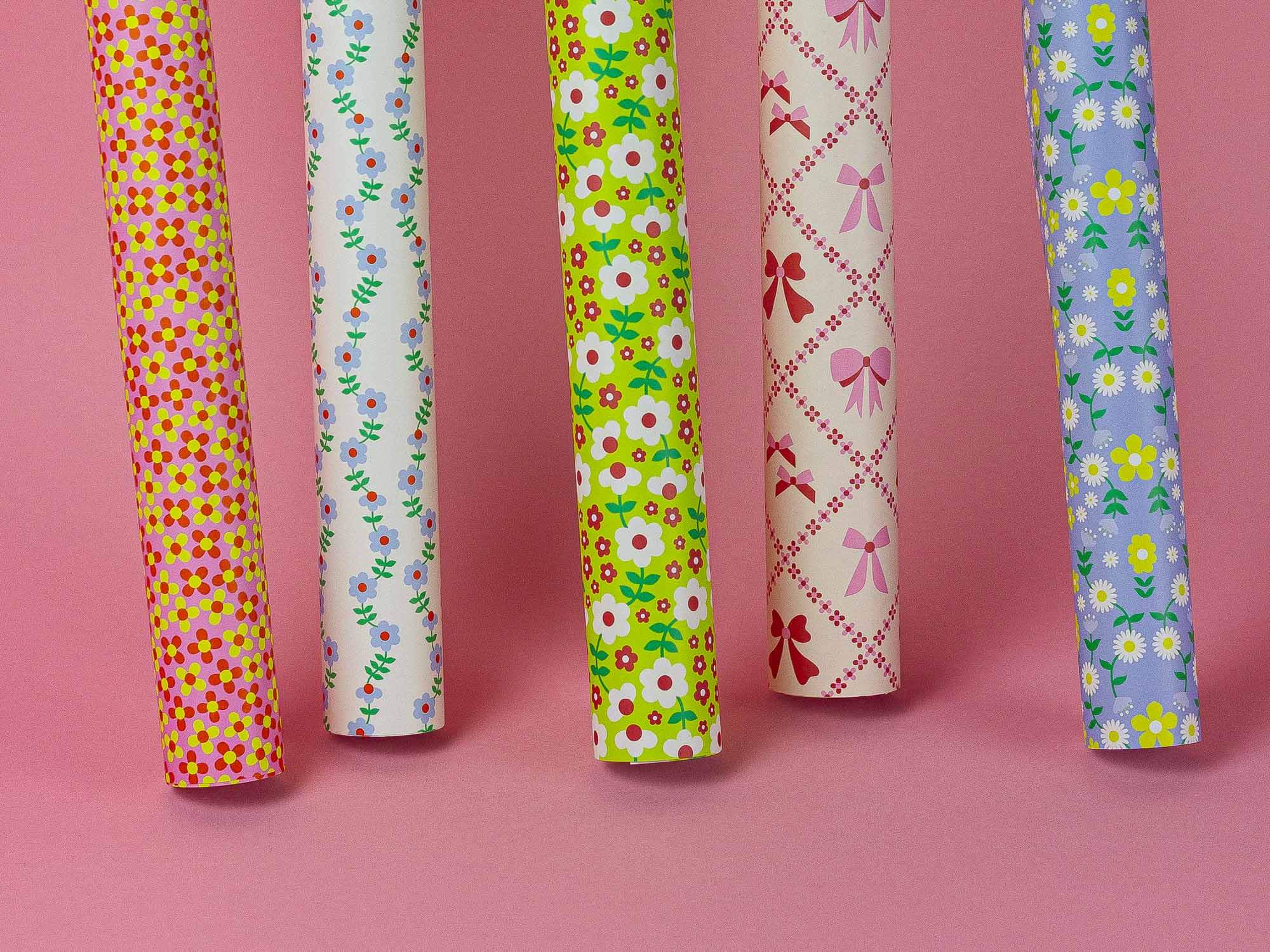 a group of different types of wrapping paper on a pink background