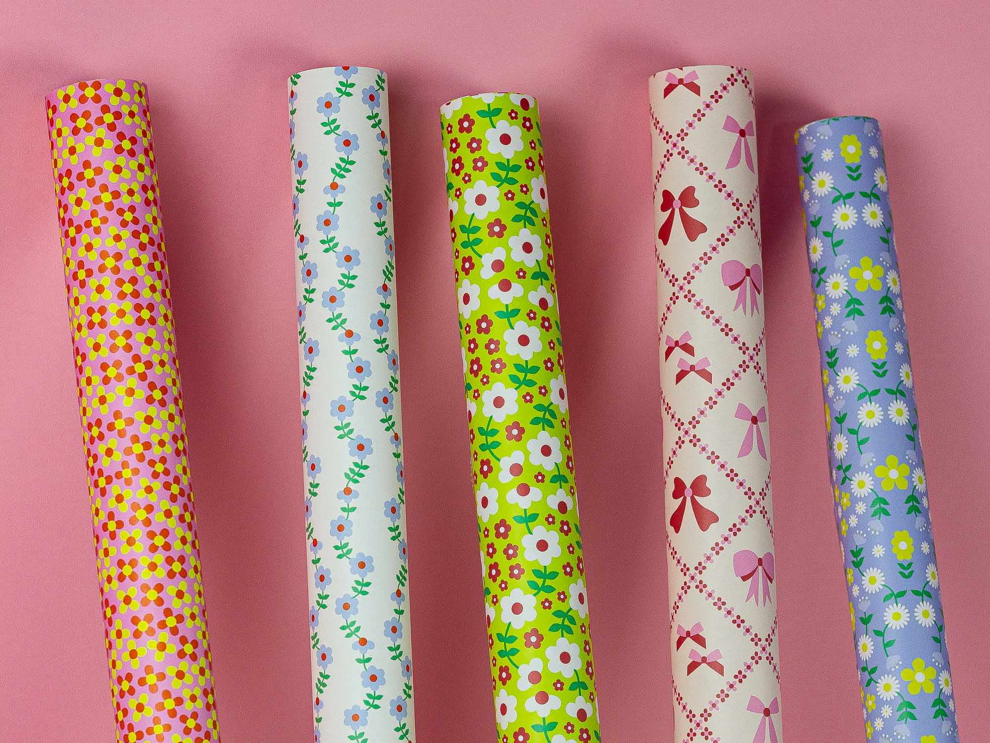 a row of different colored wrapping paper on a pink surface
