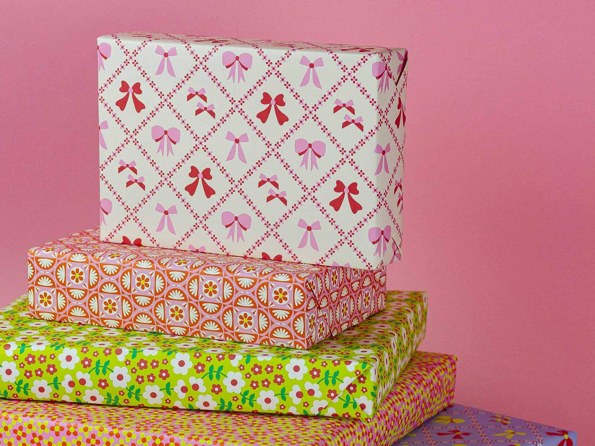 a stack of wrapped presents against a pink background