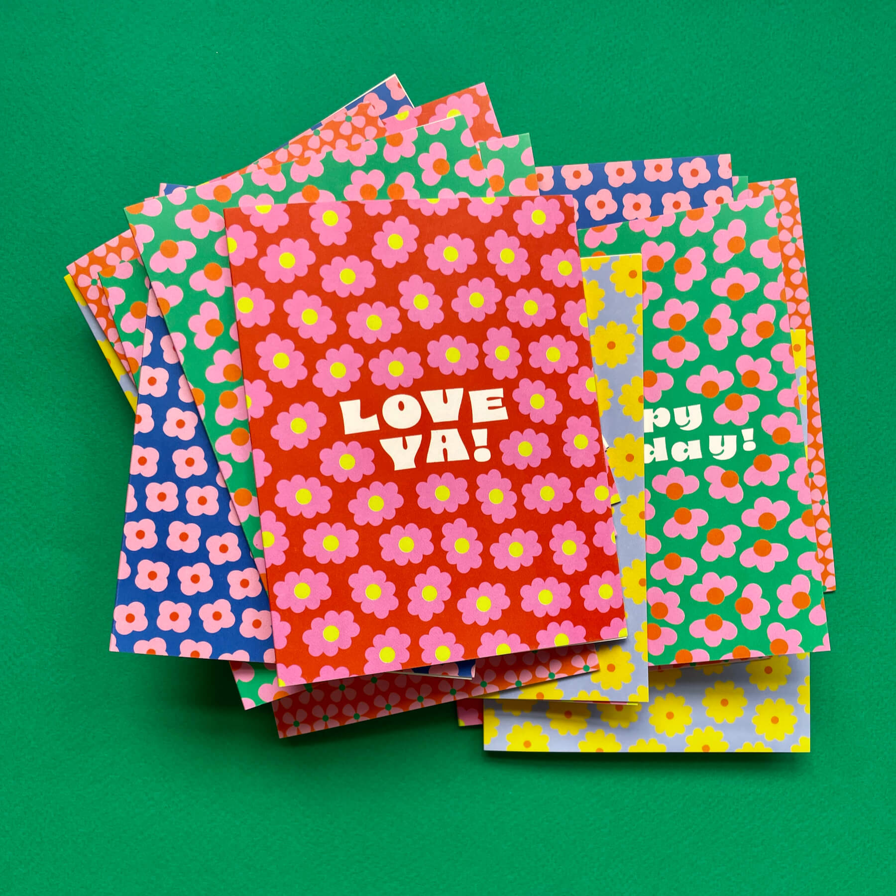 a pile of colorful notebooks sitting on top of a green surface