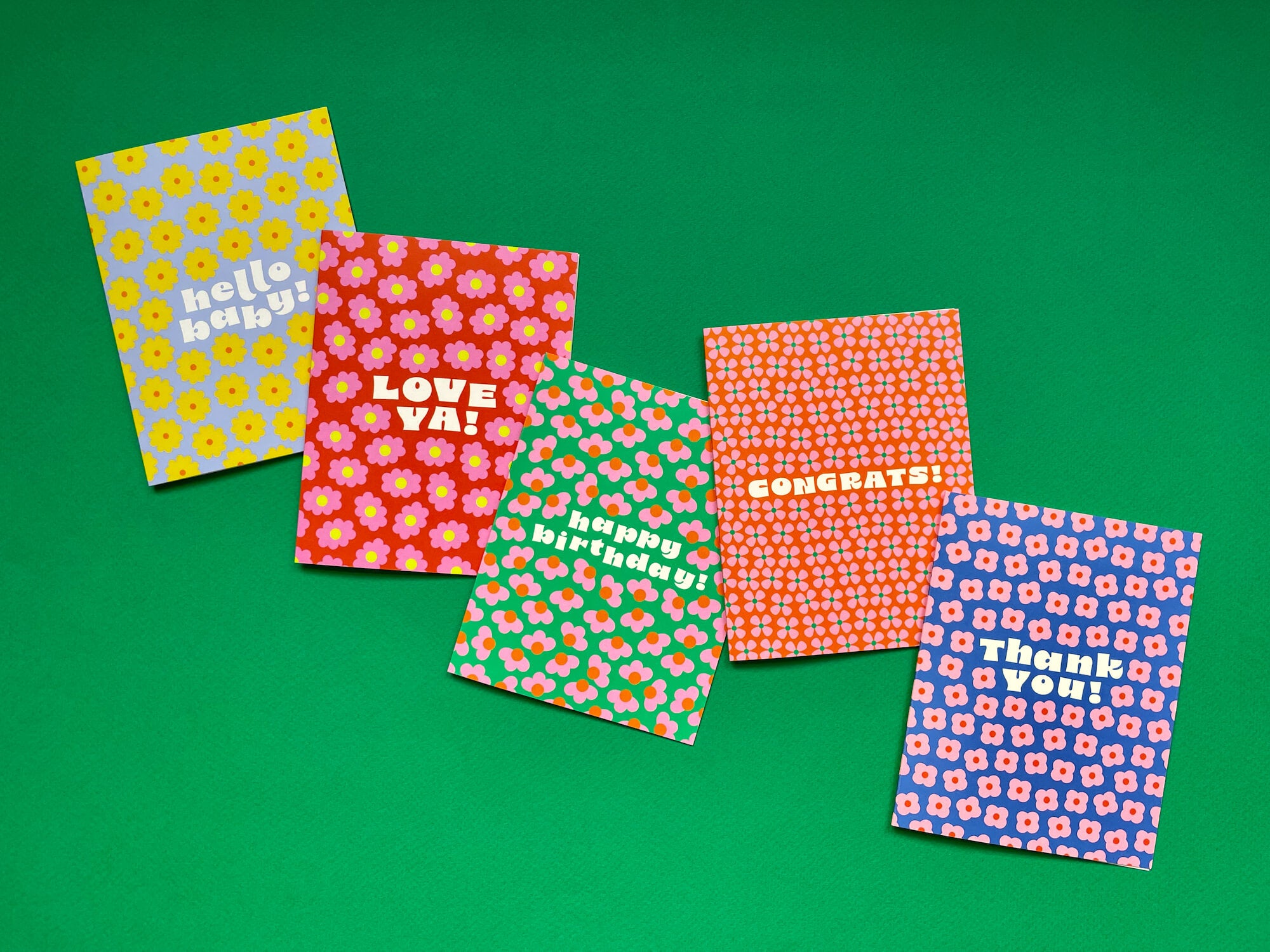 a group of four greeting cards sitting on top of a green surface