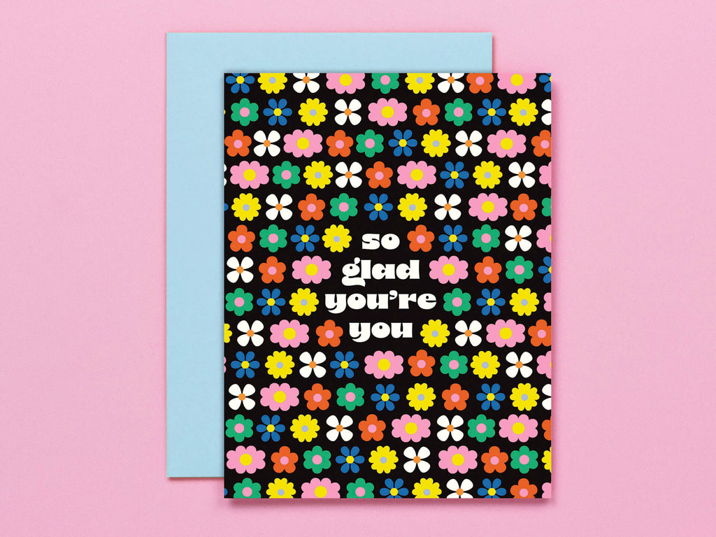 A colorful greeting card with a floral pattern and the text 'So Glad You're You' on it, paired with a coordinating envelope.