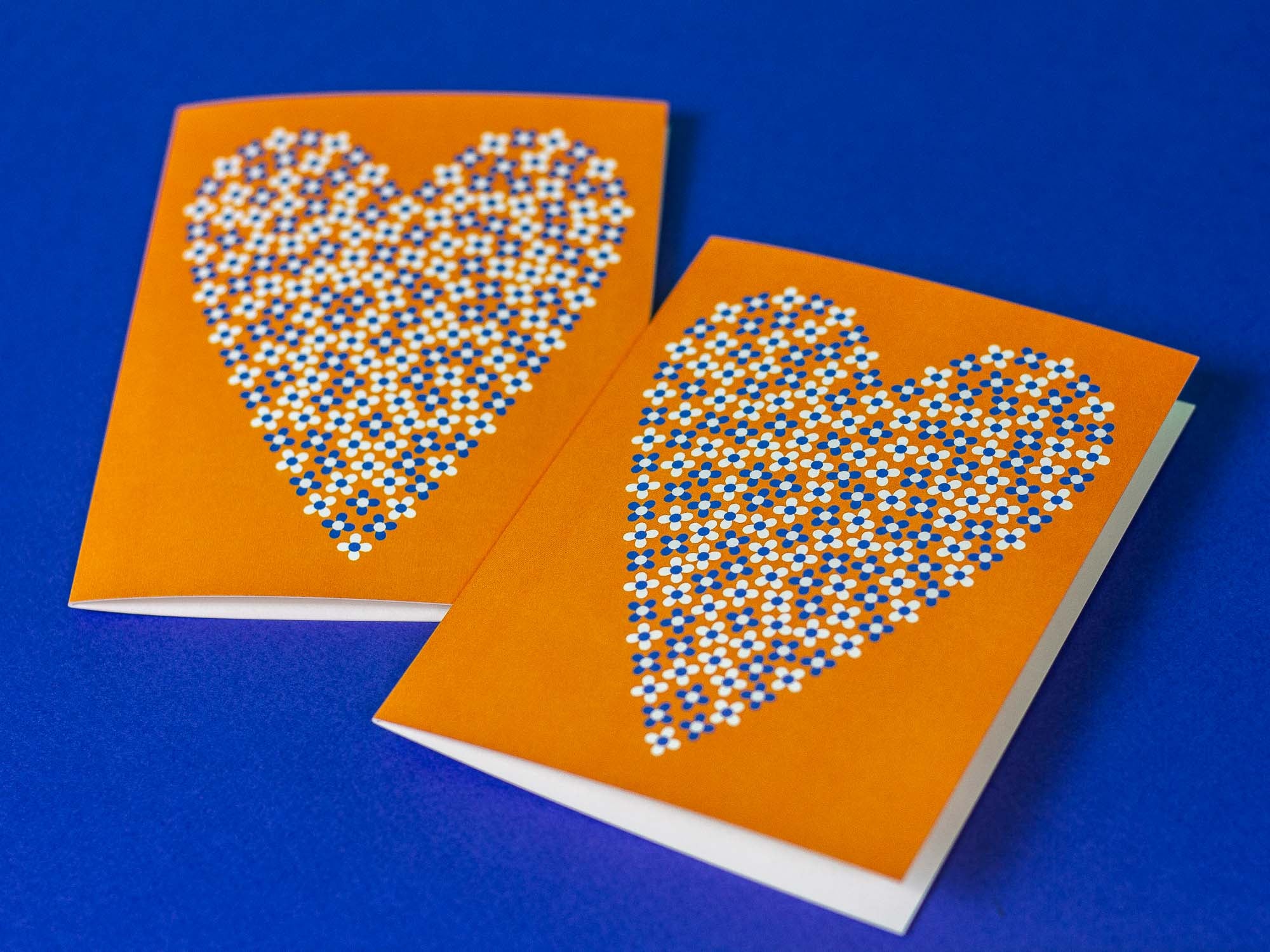 two orange cards with white and blue dots in the shape of a heart