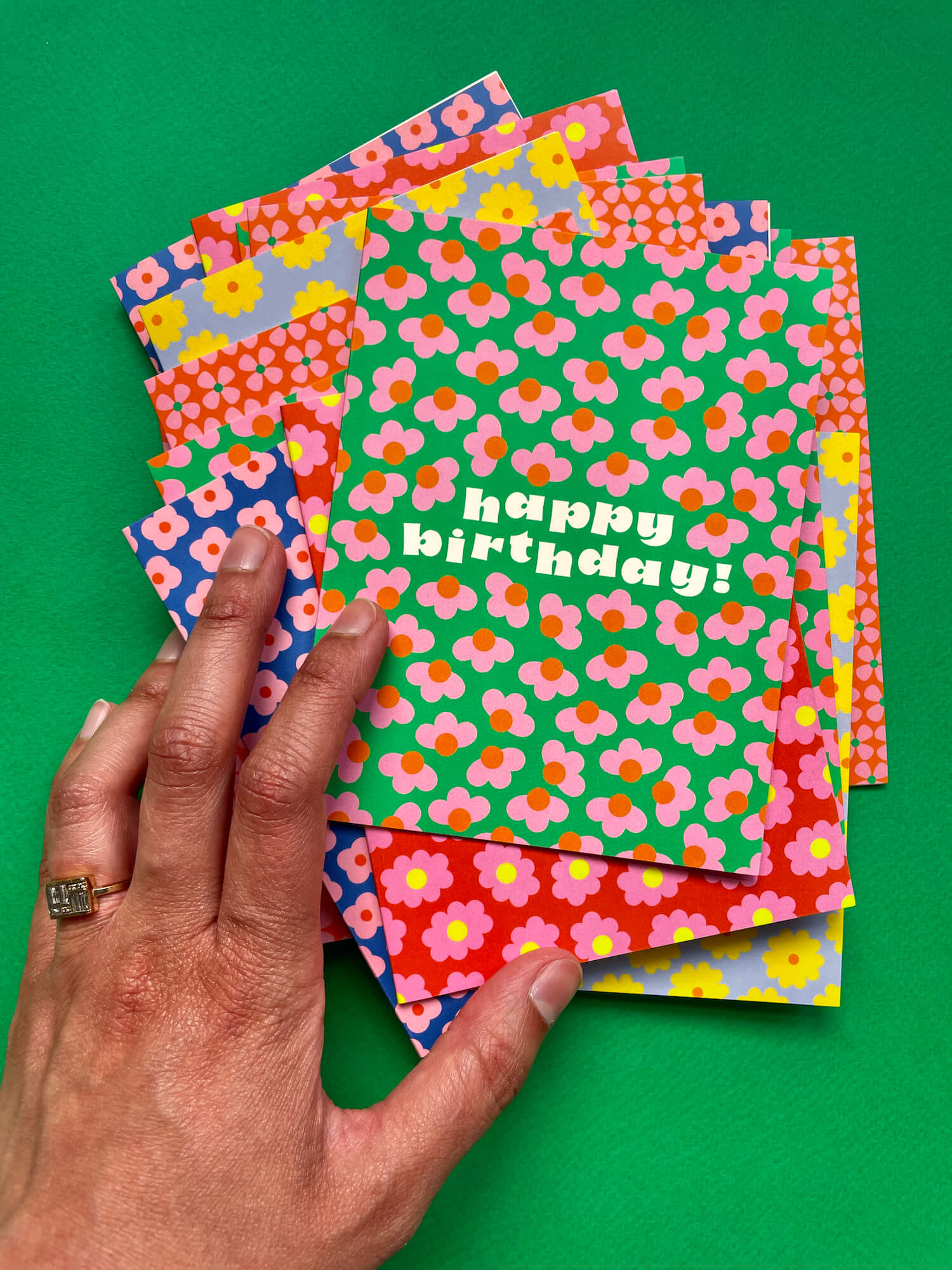 a hand holding a birthday card on top of a green surface